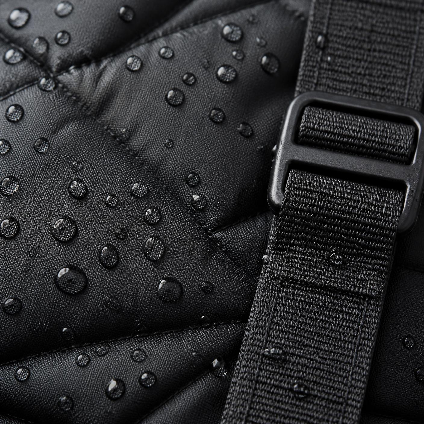 Close-up of water beading on the quilted waterproof face beside a strap and buckle
